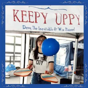 A woman plays a game of keep up with a blue balloon.